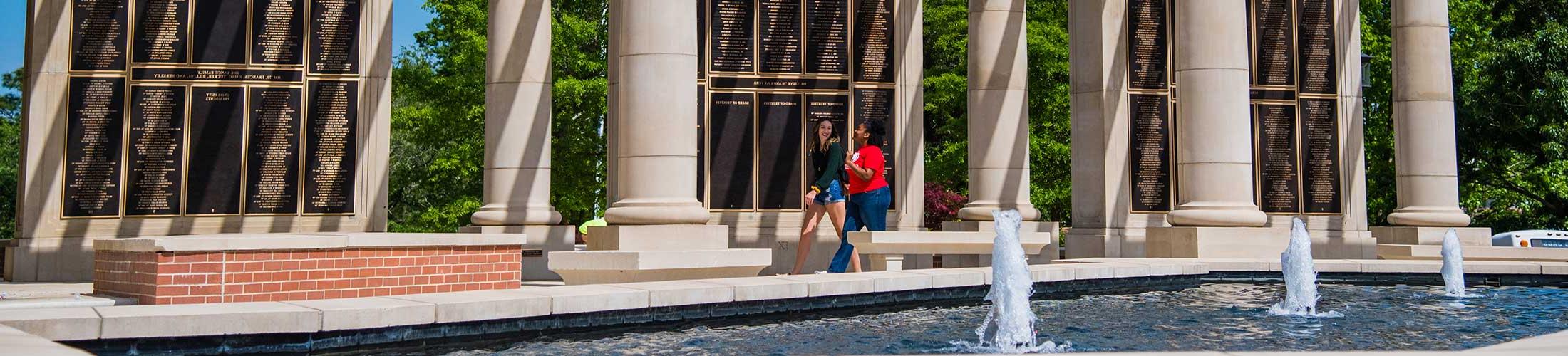 Students walking in front of the Alumni Wall.